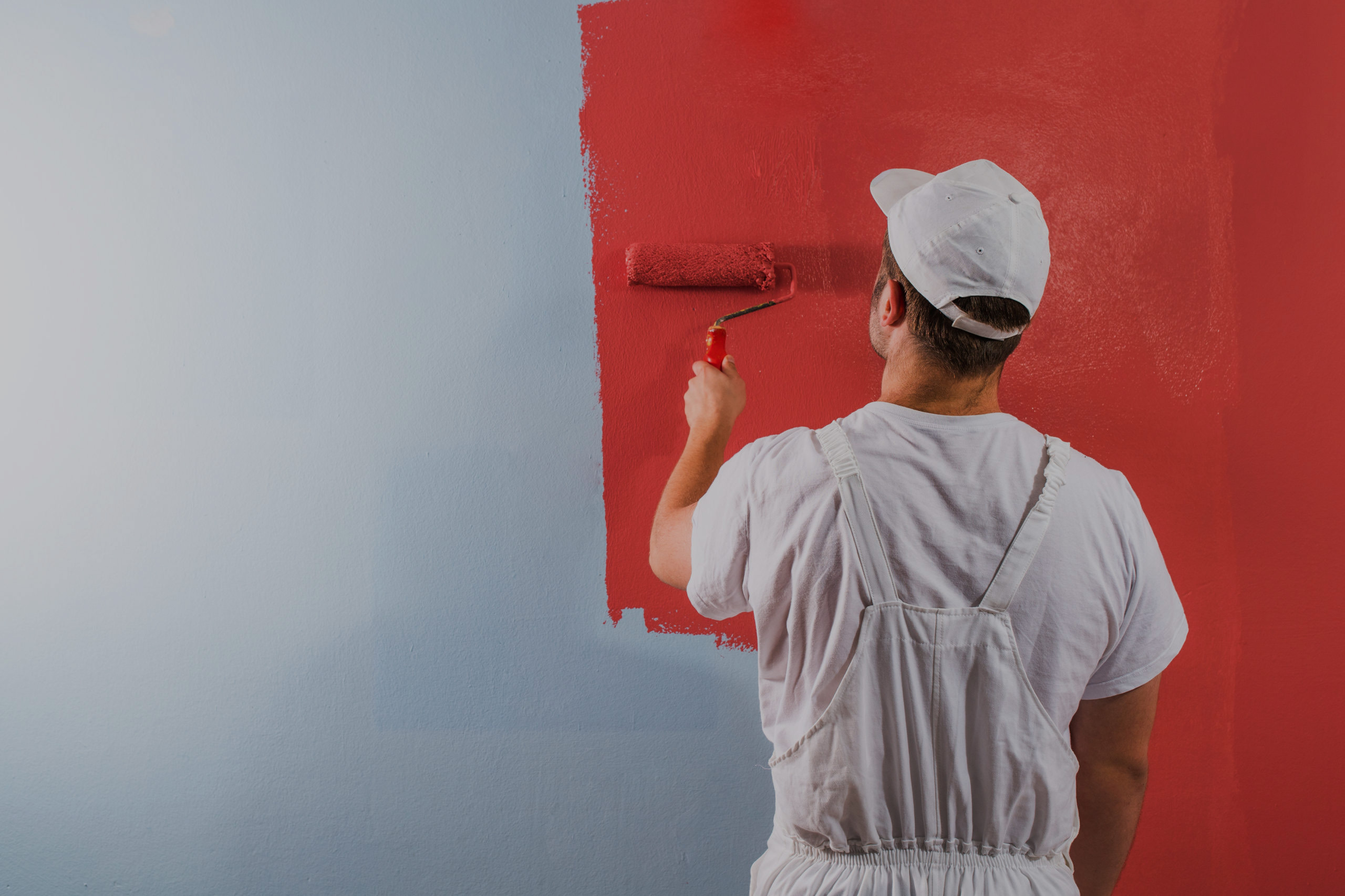 Painter painting a wall red, showcasing The Painting Doctor's expert painting services in Sterling, IL.